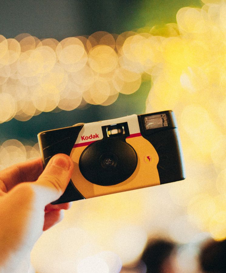 Одноразовая камера Kodak Power Flash в руке на фоне вечерних огней
