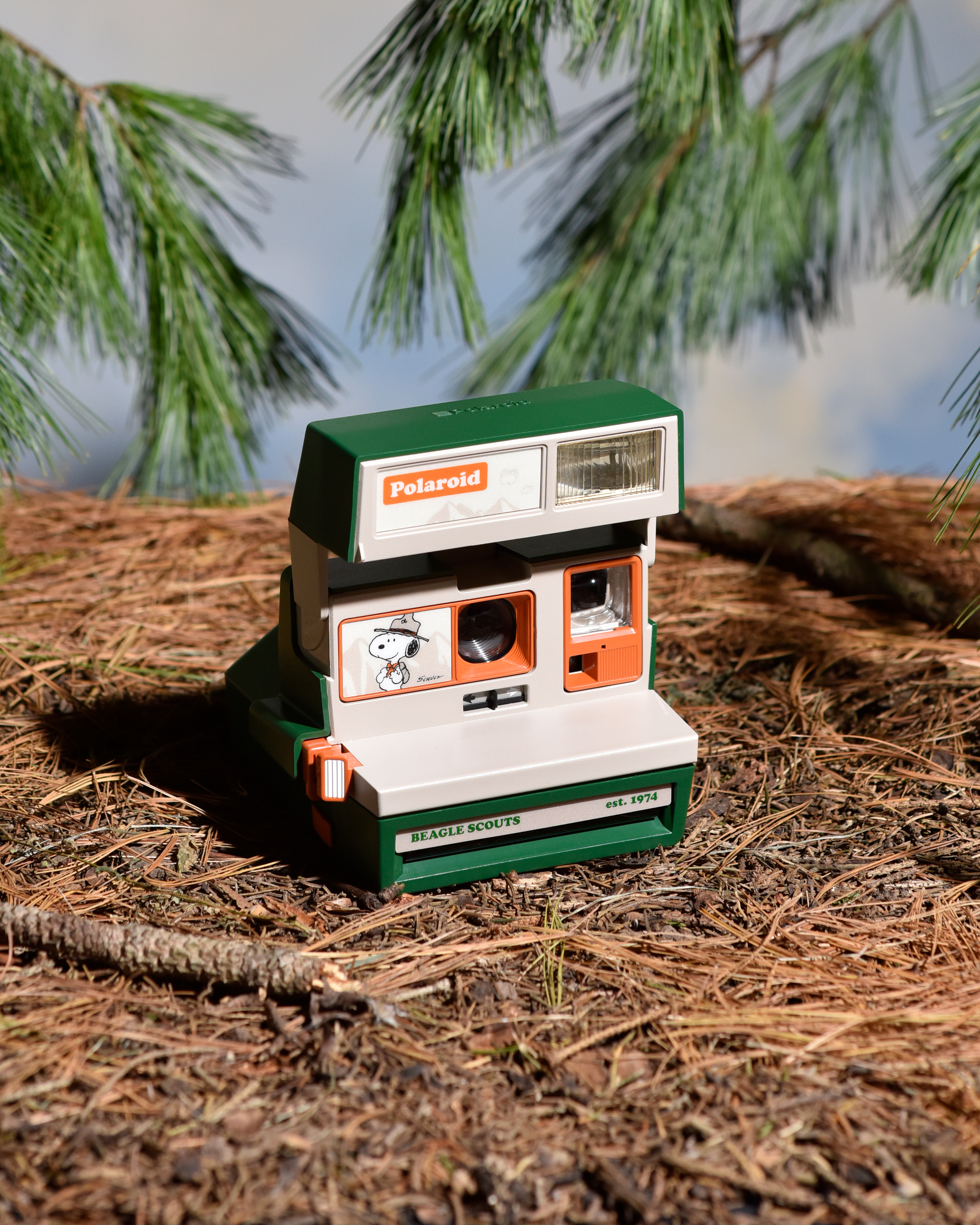 Камера мгновенной печати Retrospekt Polaroid 600 Peanuts Beagle Scouts среди сосновых ветвей